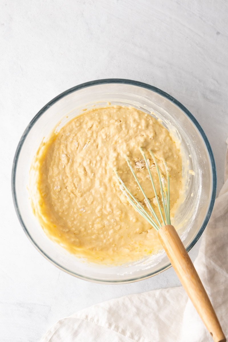 Ingredientes secos y húmedos mezclados en un recipiente de vidrio con un batidor, como se ve desde arriba