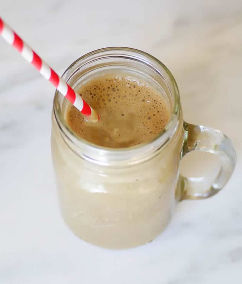 Vaso de batido vegano de proteína de mantequilla de maní con una pajita para beber